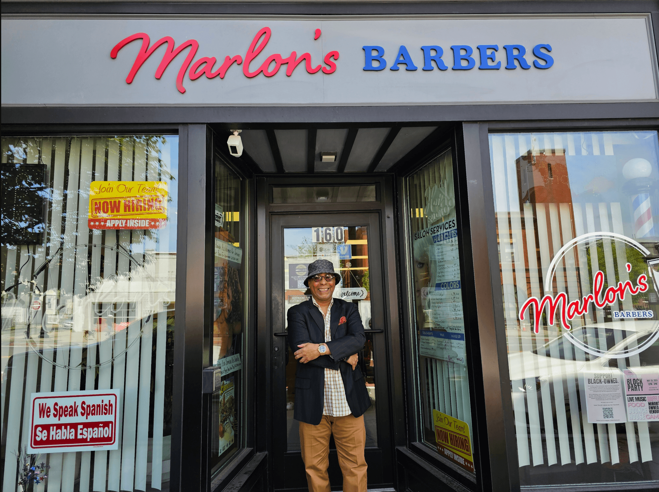 Marlon's Barbers storefront on Broadway Street in Somerville, with the owner standing in the doorway